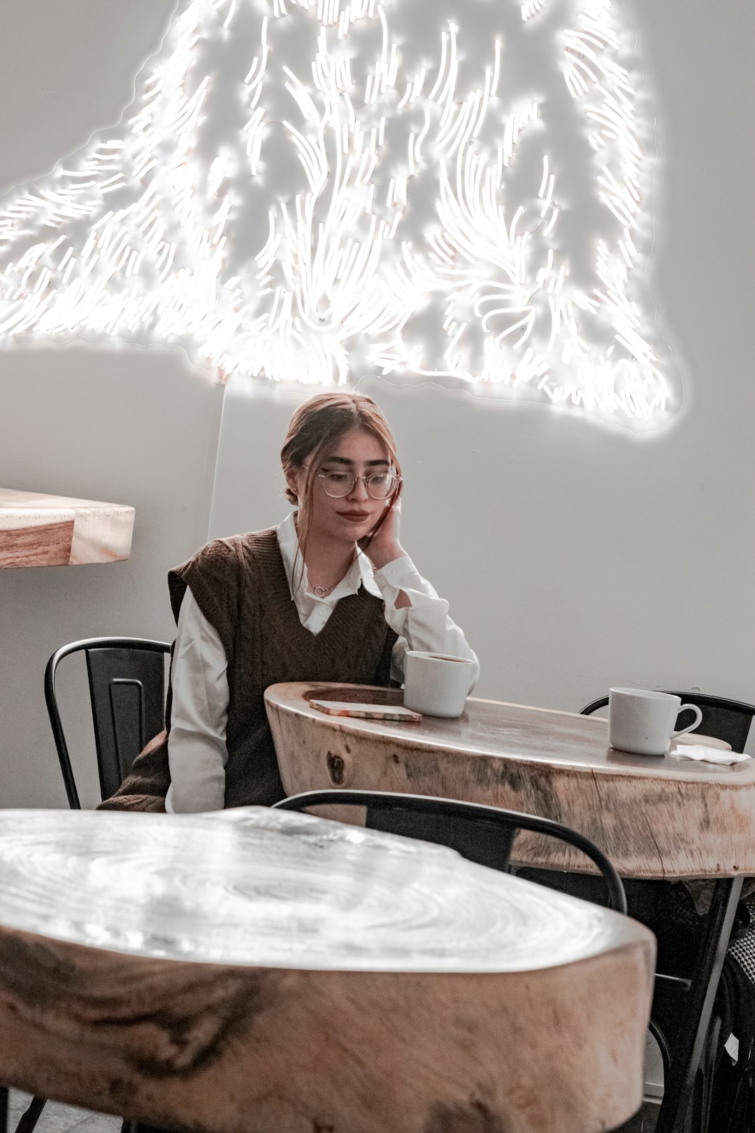 a woman sitting at a table with a cup of coffee