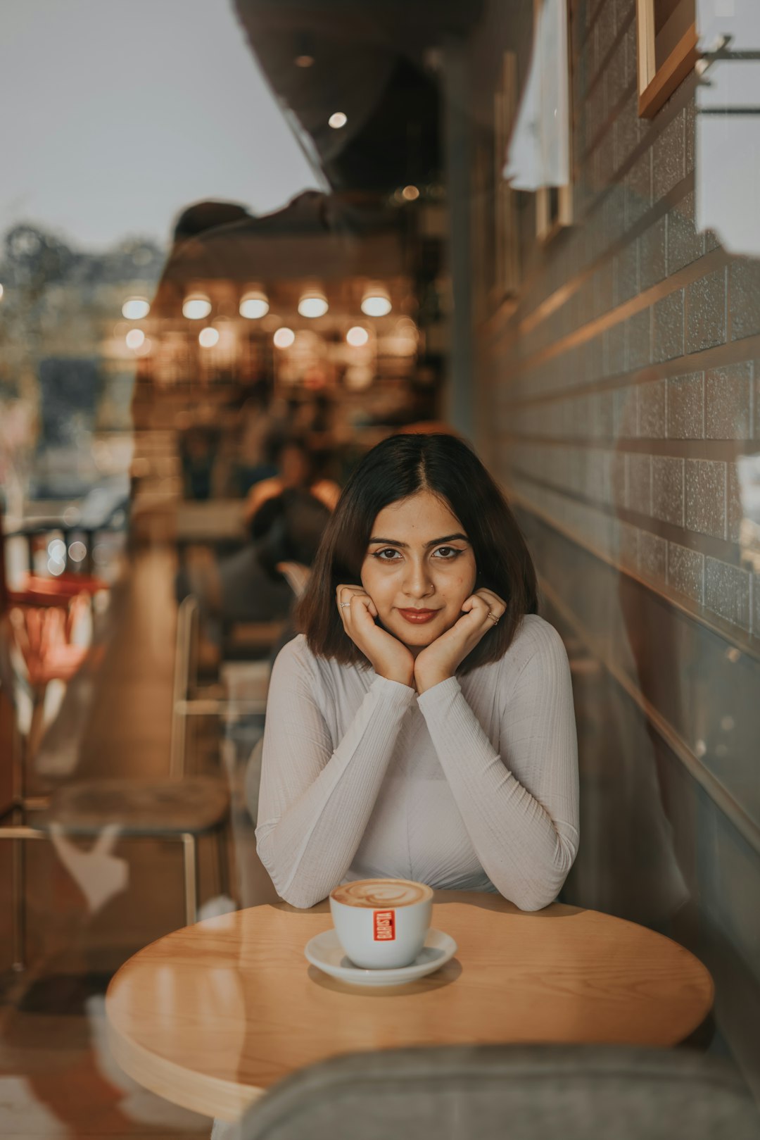 a woman sitting at a table with a cup of coffee