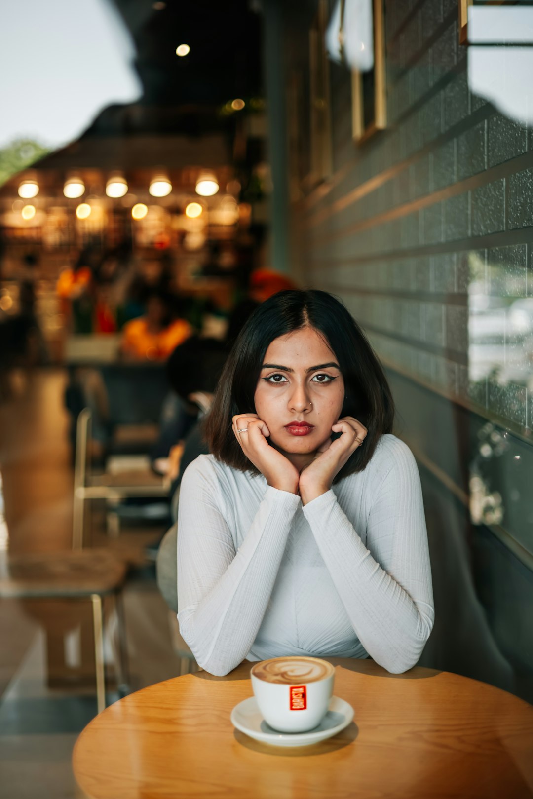 a woman sitting at a table with a cup of coffee