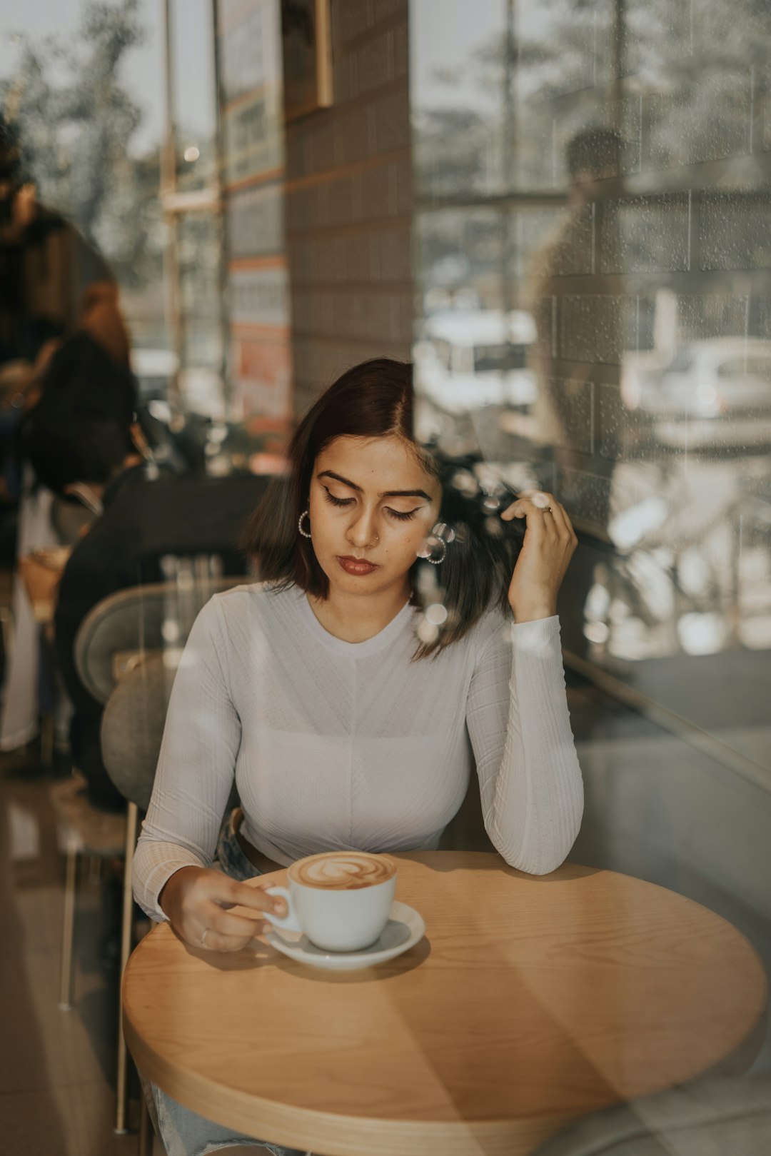 a woman sitting at a table with a cup of coffee