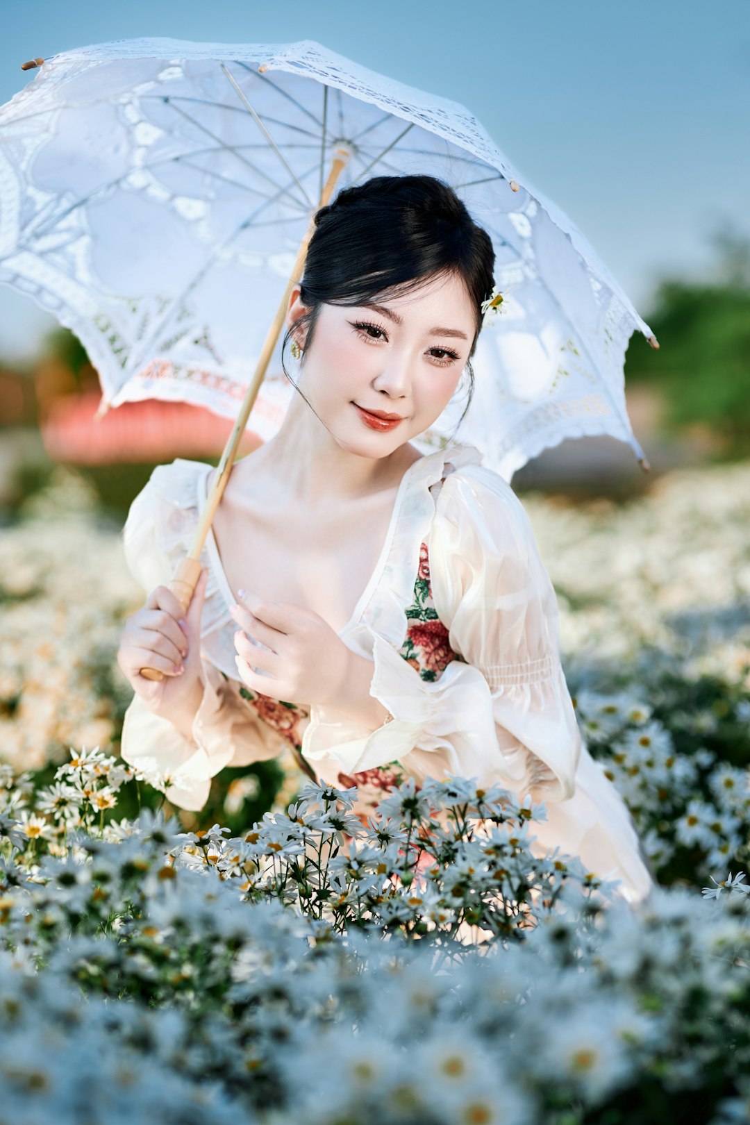 Woman holding umbrella in field of white flowers