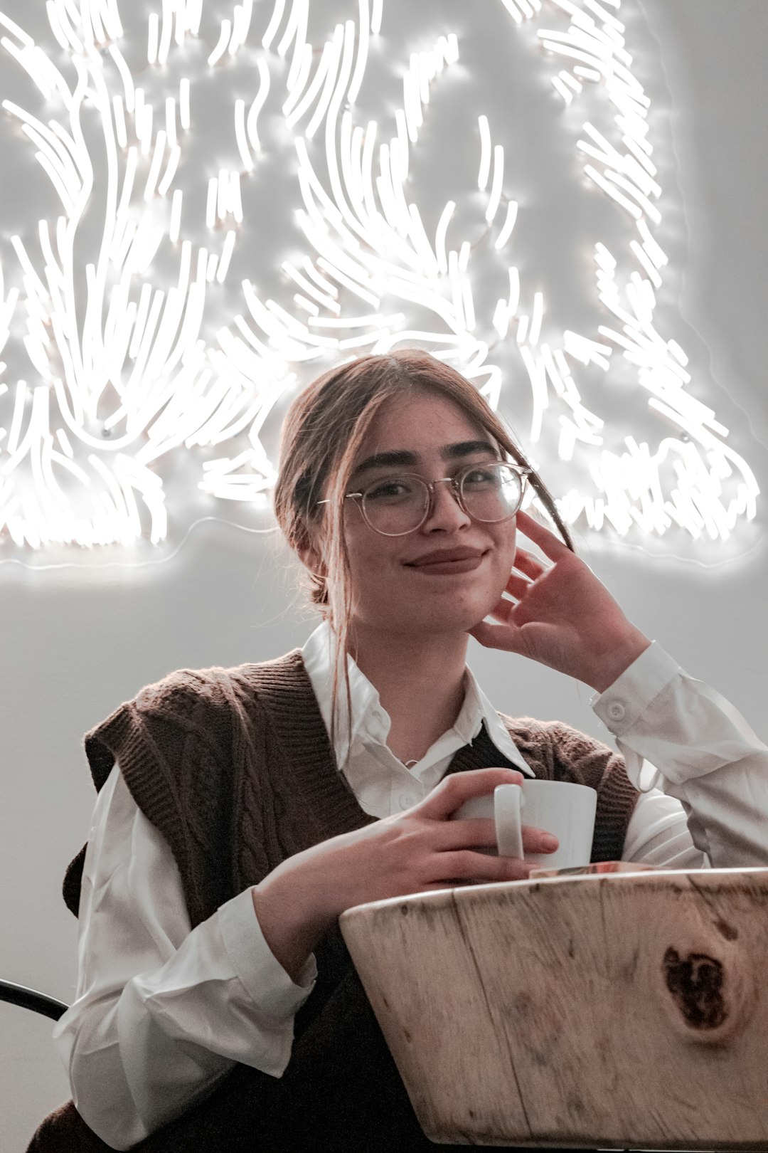 a woman sitting at a table with a cup of coffee